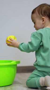 Küçük çocuk dizlerinin üzerinde sürünerek lavaboya yaklaşıyor. Çocuk küvetin içine sarı bir top koyar ve oraya gitmeye çalışır ama başarısız olur. Dikey video