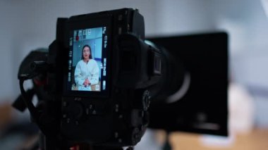 Modern kamera görüntüsü, konuşan bir kadın video kaydediyor. Stüdyoda blog ya da vlog oluşturma. Kapatın. Bulanık arkaplan.