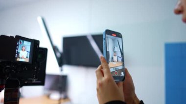 Telefondaki görüntüler ve profesyonel kamera. Kadın blogcuyla video kaydeden tanınmamış bir kadın. Bulanık arkaplan.
