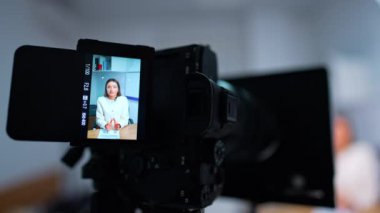 Güzel beyaz bir bayanı konuşurken gösteren bir kamera görüntüsünden uzaklaşmak. Modern bir blog için video kaydediyorum. Bulanık arkaplan.