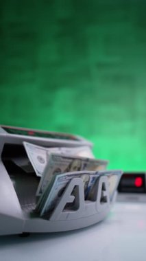Para sayma makinesinde 100 banknot sayılıyor. Kapatın. Yeşil zemin. Dikey video.