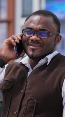 Siyahi derili iş adamı dışarıda bir telefon görüşmesi yapıyor. Belediye binasının arka planında telefonu olan Afro-Amerikan bir adamın portresi. Dikey video