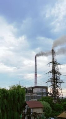 Doğanın içinde bacalar üretiyor. Fabrikadan çıkan dumanla zararlı sanayi bölgesi. Kırsal kesimde yüksek voltajlı elektrik kuleleri var. Hava kirliliği. Dikey video