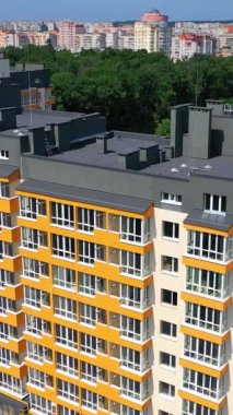 Şehirdeki modern mimarinin dış cephesi. Renkli duvarları ve gri çatısı olan yeni bir apartman. Yeni inşa edilmiş apartman blokları. Hava görüntüsü. Dikey video