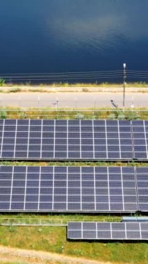 Yolun yakınındaki güneş panelleri. Güneşli piller mavi su arka planında güneşten ekolojik enerji toplarlar. Sürdürülebilir enerji. Hava görüntüsü. Dikey video