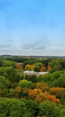 Parkın yemyeşil bahçesindeki güzel saraya yaklaşıyoruz. Arka planda bulutlu bir gökyüzü. Hava görüntüsü. Dikey video