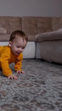 Oyuncak piramidi geçerek yerde sürünen sevimli çocuk. Küçük çocuk içeride eğleniyor. Dikey video