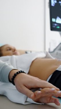 Hamile, beyaz bir kadın kocasının elini tutuyordu. Çift ultrason muayenesinden önce endişeli. Arkaplan bulanık. Dikey video