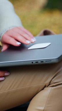 Dişi eller dizlerinin üzerinde bej pantolonla dizlerinin üzerine çökmüş dizüstü bilgisayarı açar. Dışarıda oturan bayan ofis dışında çalışacaktır. Dikey video