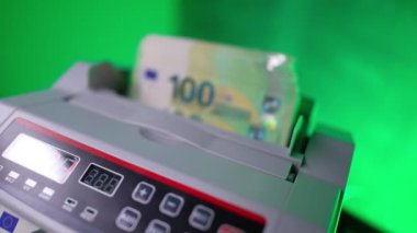 Kadının eli para sayma makinesindeki 100 'lük banknotları geri itiyor. Teçhizatta bir yığın hızla sayılır. Kapat..