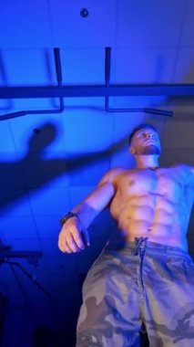 Güçlü vücutlu bir atlet spor salonunda egzersiz yapmaya çalışıyor. Aşağıdan bak. Dikey video