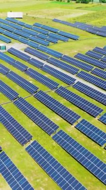 Yenilikçi fotovoltaik bitki. Yeşil doğal manzara üzerine sıralanmış güneş panelleri. Yenilenebilir enerji. Hava görüntüsü. Kamera geri gidiyor. Dikey video