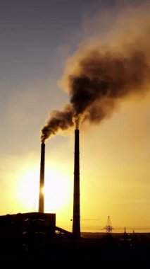 Kara fabrika geçmişi. Akşamları iki borusu olan bir fabrika. Gün batımında borulardan kirli emisyonlar dökülüyor. Dikey video