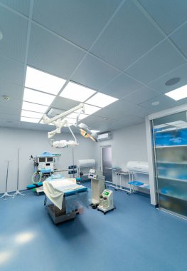 Yüksek teknoloji cerrahi odası. Parlak, temiz cerrahi odası gelişmiş tıbbi ekipmanlar, ameliyat masası ve prosedürler için yeterli ışıklandırma içeriyor..