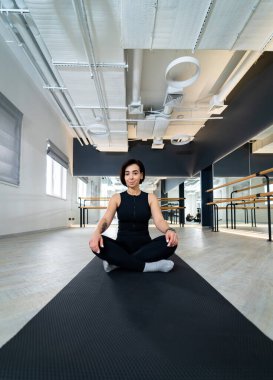 Modern stüdyoda yoga yapan bir kadın. Bir kadın parlak, çağdaş bir yoga stüdyosunda bacak bacak üstüne atarak antrenmanına odaklanır..