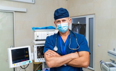 Cerrahi önlük uzmanı. Bir doktor kendine güvenerek tıbbi bir ortamda, önlük ve maske giyerken profesyonelliğini ve hazırlığını gösterir..