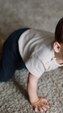 Tapılası melek bebek yerde oturup yukarı bakıyor. Çocuk ayağa kalkıyor ve kameraya doğru geliyor. Kapatın. Dikey video