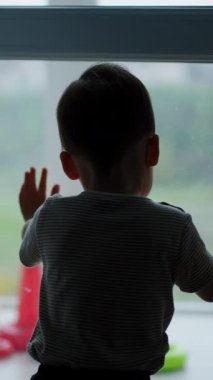 Çevik küçük çocuk kapıyı açıyor. Çocuk oyuncaklarının olduğu balkona yürüyor. Dikey video