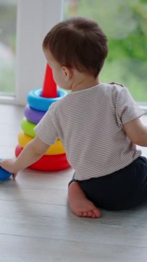 Kafkasyalı bir çocuğun piramitle oynamasının arka görüntüsü. Huzurlu bir çocuk balkonda piramit kuruyor. Dikey video