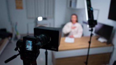 Bir elini göğsüne koyan bir kadın diğer elini karnına koyup kameraya konuşuyor. Kadın blogcu sağlık blogu için içerik kaydediyor.