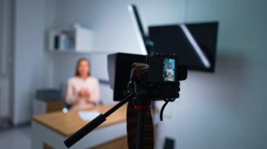 Modern kamera bir kadın blogcunun videosunu çekiyor. Kameranın görüntüsüne yaklaşıyoruz. Bulanık arkaplan.