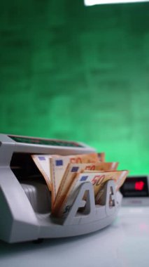 Kadın eli banka ekipmanına para koyar. Otomatik para sayma makinesinde hesaplanan 50 Euro destesi. Dikey video.