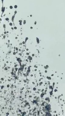 Çeşme suyu damlacıklarının güneş ışığında yakın plan çekimi. Su sıçrıyor. Yavaş çekim Dikey video