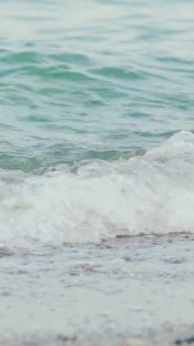 Denize yakın kumda gezinen bir kadın. Genç bayanın bacakları. Ağır çekim. Dikey video