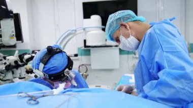 Cerrahi hoparlör takan bir doktorun kafasından vurulmuş. Cerrah ameliyatta hastanın üzerine eğildi.