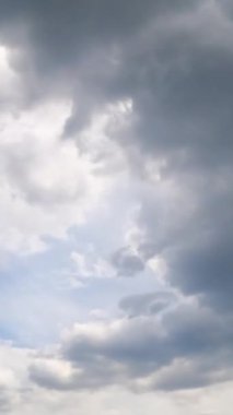 Atmosferde gri fırtınalı bulutlar oluşuyor. Güneş bulutların arkasında gizlidir. Zaman ayarlı. Dikey video