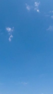 Gökyüzündeki birkaç küçük, yumuşak bulut daha büyük bulutlara dönüşür. Düşük perspektiften yaz gökyüzü. Zaman ayarlı. Dikey video