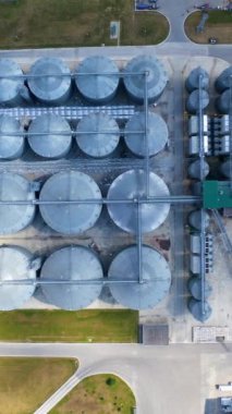 Modern bir tahıl ambarında metal teçhizat. Tarlayı tarlada tutmak için silolar. Büyük tahıl asansörlü modern endüstriyel kompleks. Üst hava manzarası. Dikey video