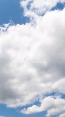 Mavi gökyüzünde şekil değiştiren bulutlar. Yumuşak bulutlar ufukta hızla süzülür. Düşük açı. Dikey video