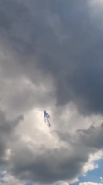 Yazın gökyüzünde kalın gri bulut oluşumu. Yağmurlu bulutlar güneşi kaplıyor. Düşük açılı zaman dilimi. Dikey video