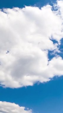 Atmosferde güzel beyaz bulutlar oluşuyor. Pofuduk bulutlar parlak yaz güneşiyle aydınlandı. Düşük açılı zaman dilimi. Dikey video