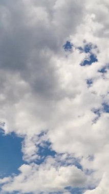 Atmosferde kabarık beyaz ve gri bulutlar var. Bulutların oluşumu düşük açılı açıdan. Zaman ayarlı. Dikey video
