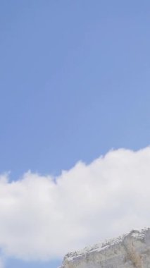 White Hill 'de kettlebell çalan bir sporcu. Siyah şapkalı ve güneş gözlüklü sporcu yaz günü dağda antrenman yapıyor. Yavaş çekim Dikey video