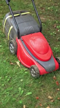 Çim biçme makinesi arka bahçede çim biçiyor. Modern makine dışarıda çim biçiyor. Bahçe işleri. Dikey video