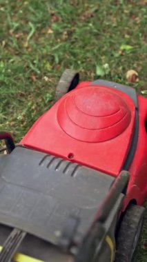 Çim biçme makinesi dışarıdaki çimleri kesiyor. Yerdeki elektrikli çim biçme makinesinin en üst görüntüsü. Çim biçme makinesiyle çim biçen bir işçi. Bahçe işleri. Dikey video