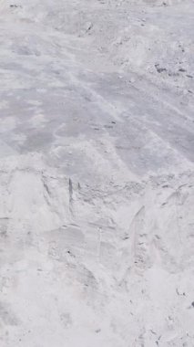 Beyaz kanyon ve bir sporcu. Tepede duran güçlü sporcuya yukarıdan bakın. Hava görüntüsü. Dikey video