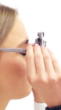 Gözler için test cihazını çıkaran genç bir kadının profili. Klinikte gözlük lensi seçimi. Dikey video