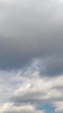 Gök mavisi gökyüzünde güzel beyaz bulut oluşumu. Bulutlar atmosferde hızla şekil değiştiriyor. Düşük açı. Zaman ayarlı. Dikey video