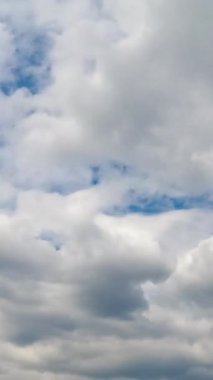Yumuşak yumuşak bulutlar gökyüzünü kaplıyor. Gündüz vakti atmosferde bulut oluşumu. Düşük açı. Zaman ayarlı. Dikey video
