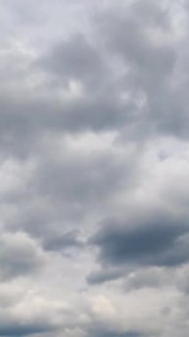 Atmosferde hareket eden gri bulutlar. Kümülüs bulutları yağmurdan önce toplanıyor. Düşük açı. Zaman ayarlı. Dikey video