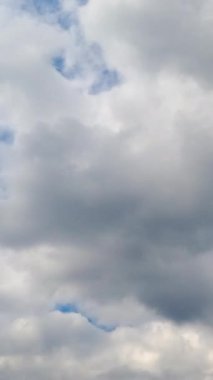 Gök mavisi, gri bulutların ardında neredeyse hiç görülmez. Atmosferde gri bulutlar birikiyor. Düşük açı. Zaman ayarlı. Dikey video