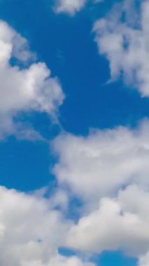 Mavi gökyüzünde biriken beyaz kümülüs bulutu. Düşük açıdan güzel bir yaz gökyüzü. Zaman ayarlı. Dikey video