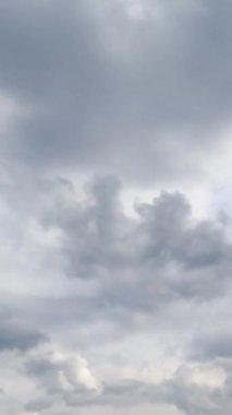 Gündüz vakti gökyüzünü kaplayan bulutlar. Atmosferdeki gri bulutlu hava alçak açıdan görünüyor. Zaman ayarlı. Dikey video