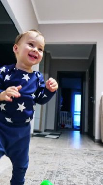 Odanın etrafında koşan mutlu gülen çocuk. Bebek kanepeye gider kediye basar ve onu korkutur. Düşük açı. Dikey video