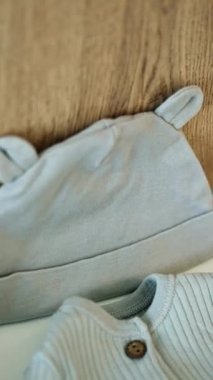 Yeni doğan bebek için şirin bir kep, gömlek ve çorap. Ebeveynler tarafından çocuk için hazırlanmış giysiler. Kapatın. Dikey video