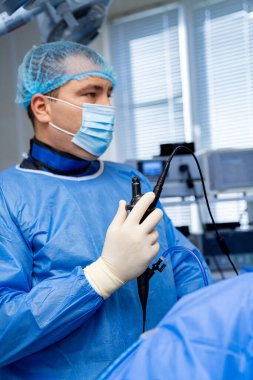 Cerrah ameliyata hazır. Önlüklü bir tıp uzmanı iyi donanımlı bir ameliyathanede endoskop hazırlıyor..